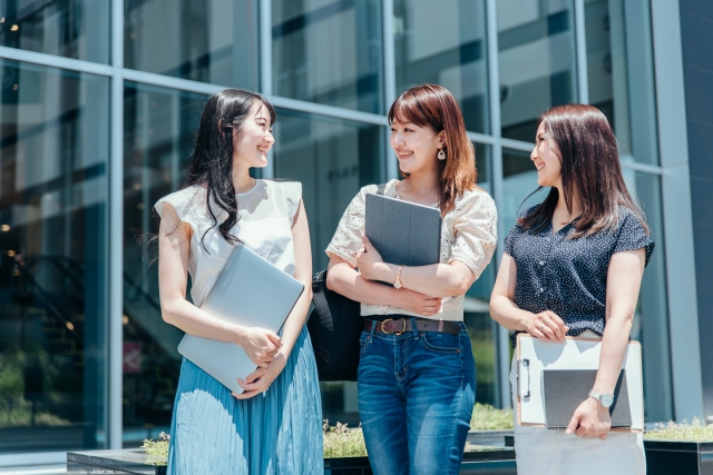 キャンパスで笑顔で話す女子大学生