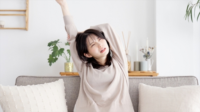 眠気覚ましに伸びをする女性