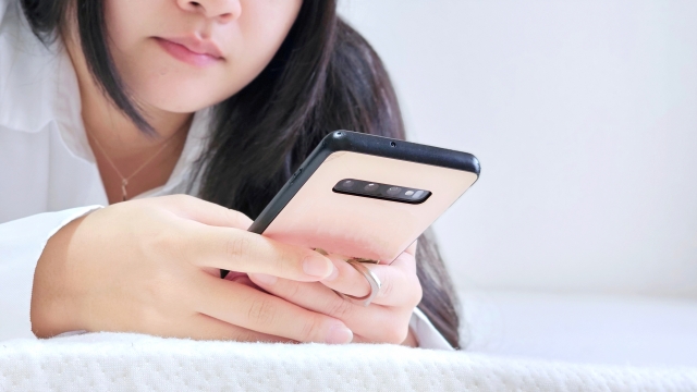 不安そうに携帯を見る女性