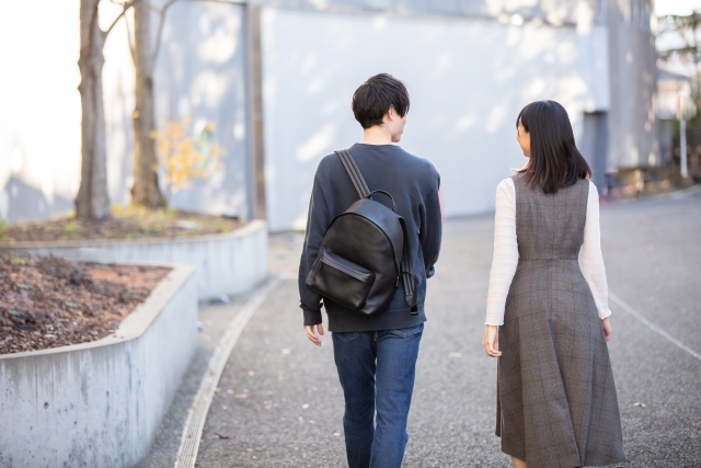大学生の男女がキャンパス近くを歩きながら自然に会話し出会いのきっかけを作っているイメージ