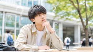 大学生で彼女ができないことに悩み、よくある質問を考える男子大学生のイメージ
