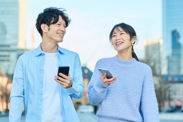 大学生の男女がスマホを持ちながら自然に会話し出会いのきっかけを作っているイメージ